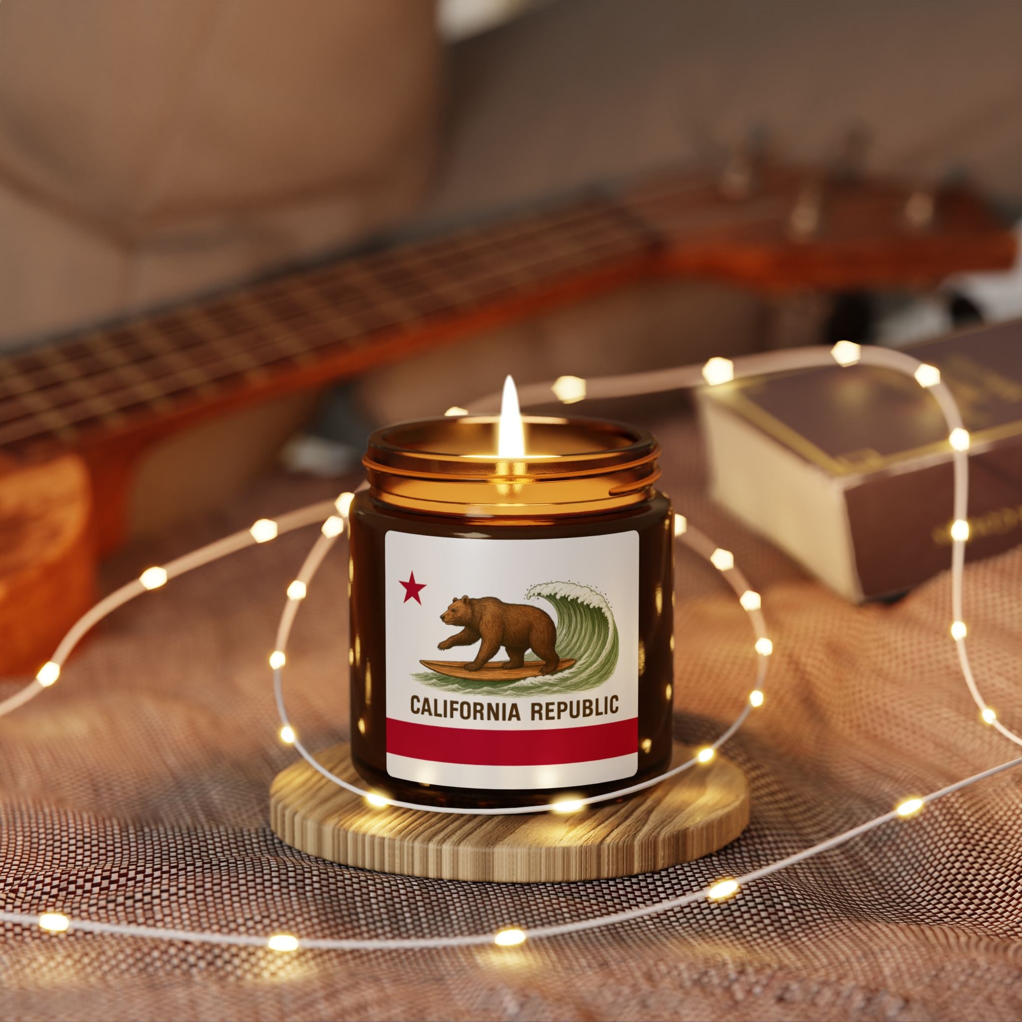 Candle with California Republic label on a wooden coaster with fairy lights, guitar in the background